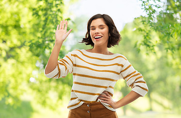 Image showing smiling woman in striped pullover waving hand