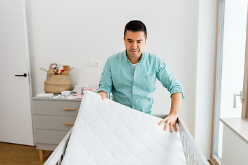 Image showing father arranging baby bed with mattress at home