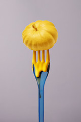 Image showing Painted small yellow pumpkin on a vertical plastic fork.