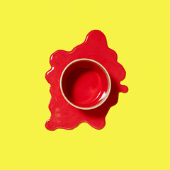 Image showing Spilled red puddle of paint with can on an yellow background.