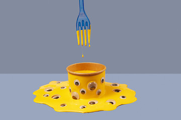 Image showing Plastic fork and drops of yellow paint above can in puddle with googly eyes.