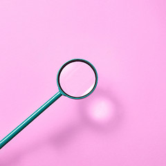 Image showing Magnifying glass above pink background with shadows.