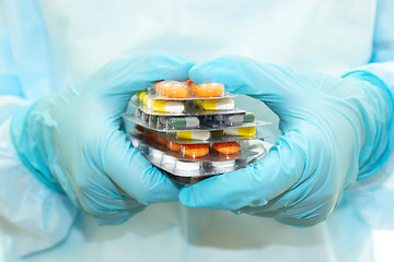 Image showing Nurse in a sterile gown and gloves holds packs of pills in blisters