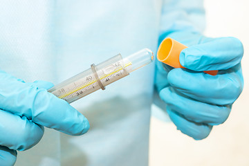Image showing Hands of nurse in sterile gown and gloves take a thermometer out of case