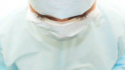 Image showing Fluffy eyelashes of surgeon in sterile surgical mask and medical gown at work