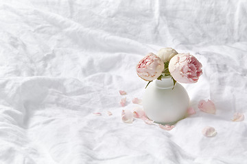 Image showing Vase with fresh roses on crumpled sheets.