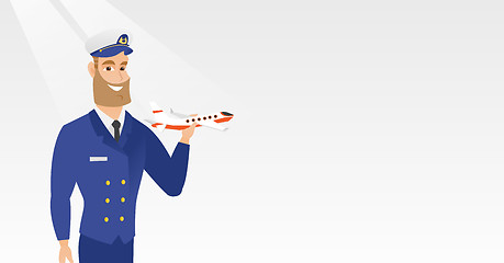 Image showing Cheerful airline pilot with the model of airplane.