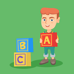Image showing Smiling caucasian boy playing with alphabet cubes.