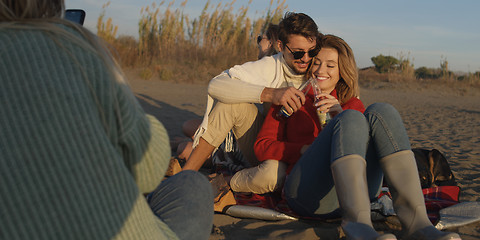 Image showing Loving Young Couple Sitting On The Beach beside Campfire drinkin