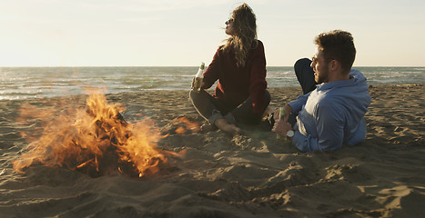 Image showing Loving Young Couple Sitting On The Beach beside Campfire drinkin