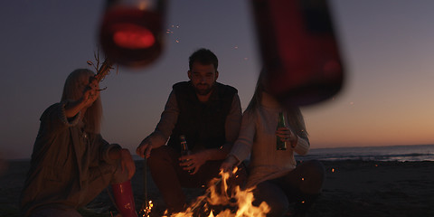 Image showing Young Friends Making A Toast With Beer Around Campfire at beach