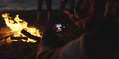 Image showing Couple taking photos beside campfire on beach