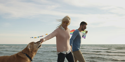 Image showing couple with dog having fun on beach on autmun day