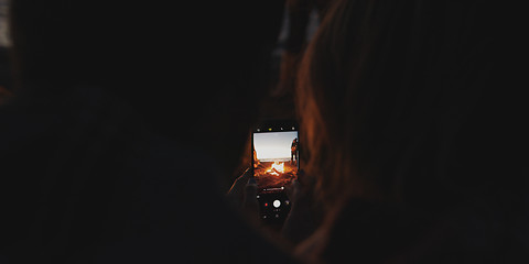 Image showing Couple taking photos beside campfire on beach