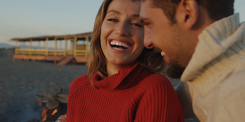 Image showing Loving Young Couple Sitting On The Beach beside Campfire drinkin