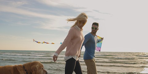 Image showing couple with dog having fun on beach on autmun day