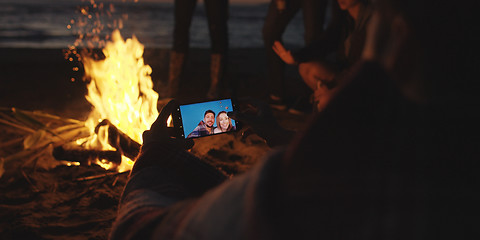 Image showing Couple taking photos beside campfire on beach