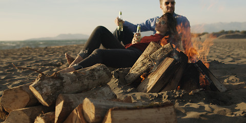 Image showing Loving Young Couple Sitting On The Beach beside Campfire drinkin