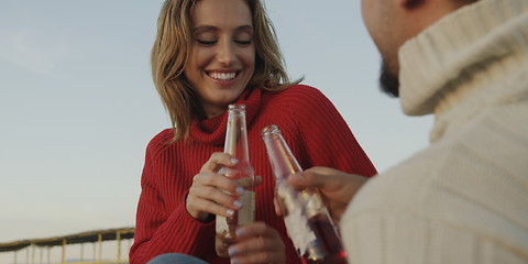 Image showing Loving Young Couple Sitting On The Beach beside Campfire drinkin