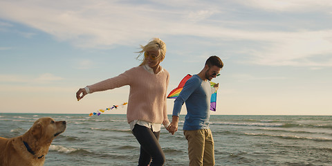 Image showing couple with dog having fun on beach on autmun day