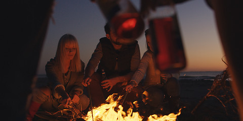 Image showing Young Friends Making A Toast With Beer Around Campfire at beach