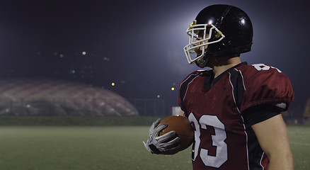 Image showing American football player holding ball while running on field