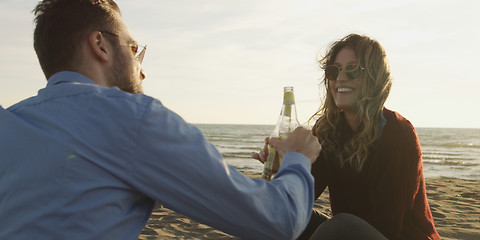 Image showing Loving Young Couple Sitting On The Beach beside Campfire drinkin