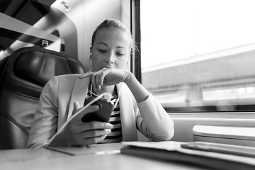 Image showing Businesswoman communicating on mobile phone while traveling by train.