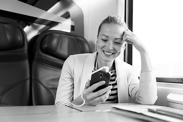 Image showing Businesswoman communicating on mobile phone while traveling by train.