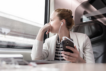 Image showing Businesswoman communicating on mobile phone while traveling by train.