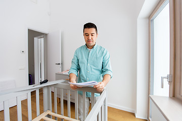 Image showing father with manual assembling baby bed at home