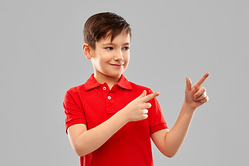 Image showing happy boy in red t-shirt pointing fingers aside