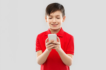 Image showing smiling little boy in red t-shirt using smartphone