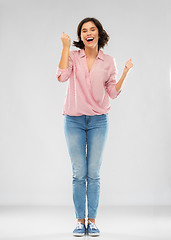 Image showing young woman in shirt and jeans celebrating success