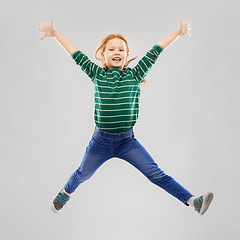 Image showing smiling red haired girl in striped shirt jumping