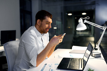 Image showing businessman with smartphone and computer at office