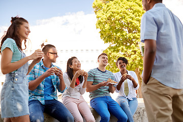 Image showing friends eating sandwiches or burgers in park