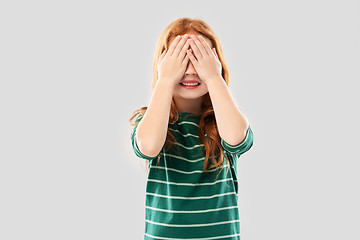 Image showing smiling red haired girl with eyes closed by hands