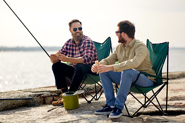 Image showing happy friends fishing and eating sandwiches