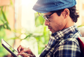 Image showing close up of man with tablet pc sitting at cafe