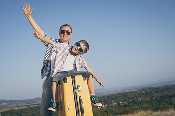 Image showing Father and son standing on the road at the day time. 