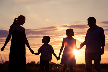 Image showing Happy family standing on the field at the sunset time. They buil