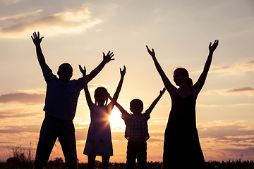 Image showing Happy family standing on the field at the sunset time. They buil