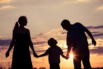 Image showing Happy family standing in the park at the sunset time.