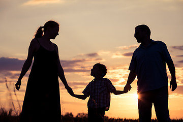 Image showing Happy family standing in the park at the sunset time.