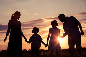 Image showing Happy family standing in the park at the sunset time.