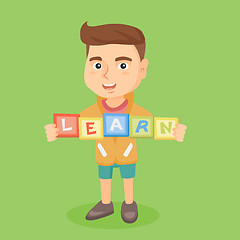 Image showing Boy holding blocks that spelling the word learn.