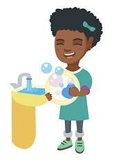 Image showing Little african girl washing dishes in the sink.