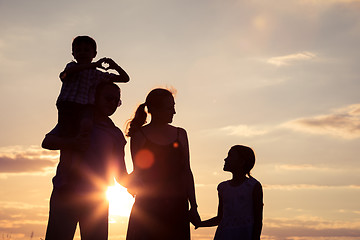 Image showing Happy family standing in the park at the sunset time.