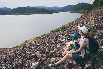 Image showing Happy family sitting near a lake at the day time.
